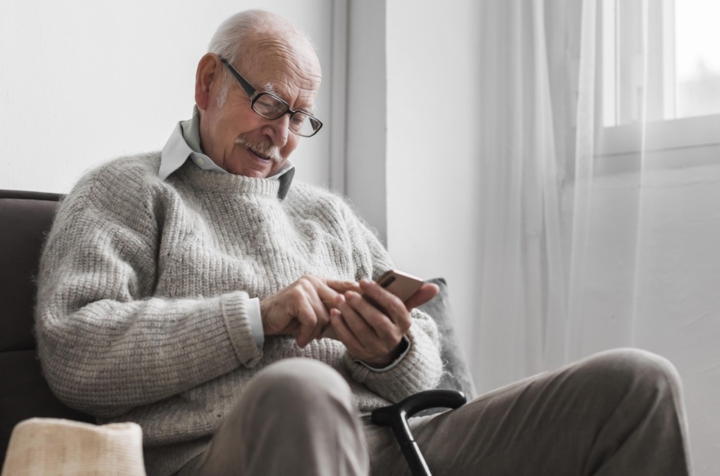 side-view-older-man-nursing-home-using-smartphone side-view-older-man-nursing-home-using-smartphone