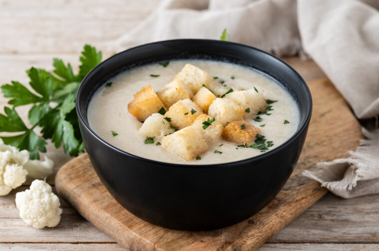 Cauliflower soup in a bowl on wooden table